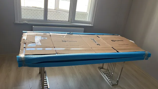 Masa yüzeyinin karton ve mavi kenar koruyucuyla kaplanması