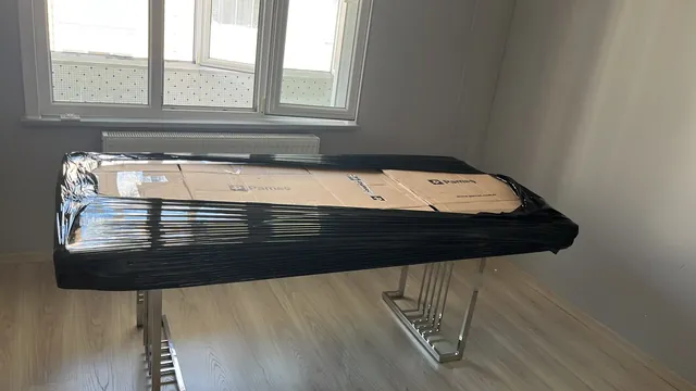 Karton ve siyah filmle tamamı korunan masa ve mobilya parçası